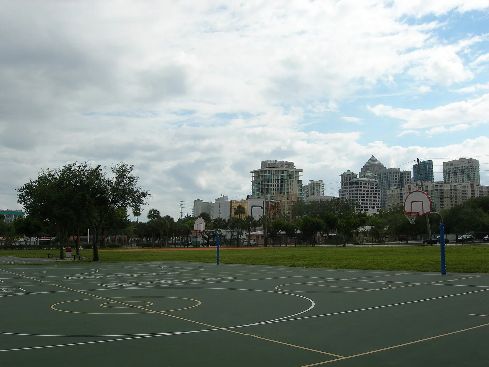 Basketball courts at a neighborhood park with the downtown Fort Lauderdale skyline behind.